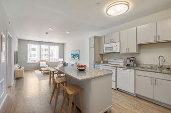 An open kitchen and dining area with a granite counter top and white appliances
